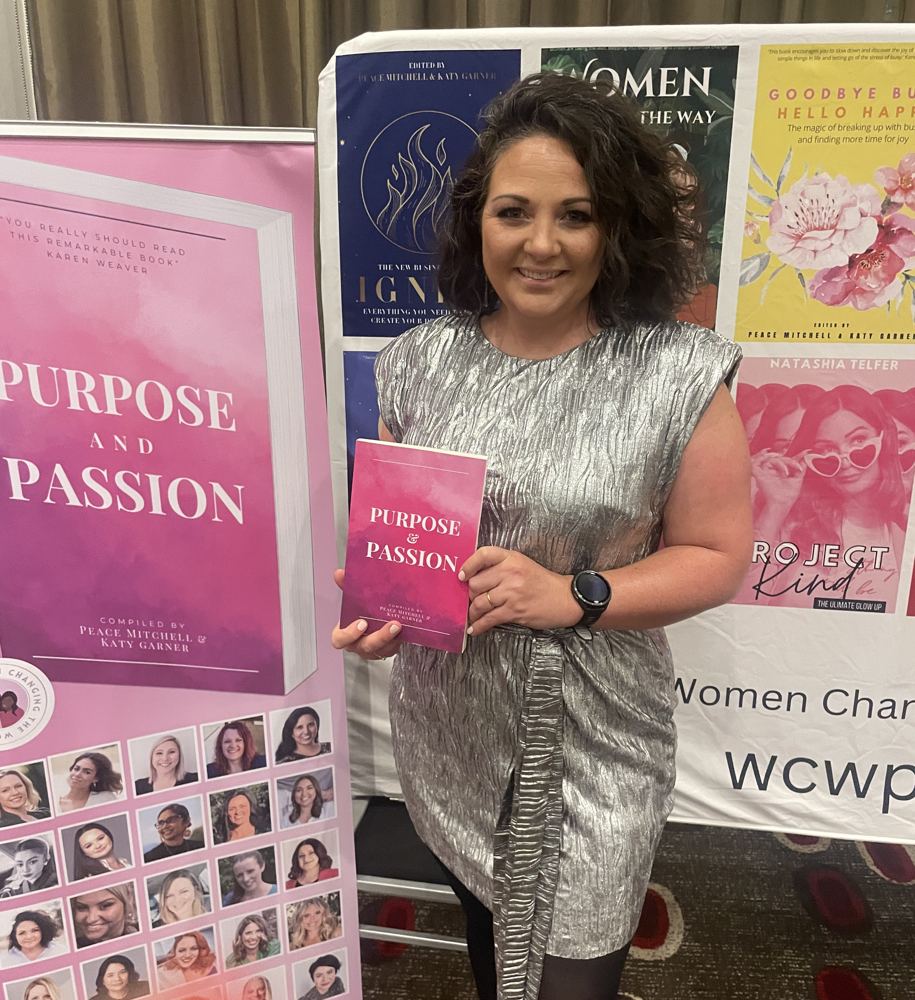 Victoria smiling, holding a copy of Purpose and Passion